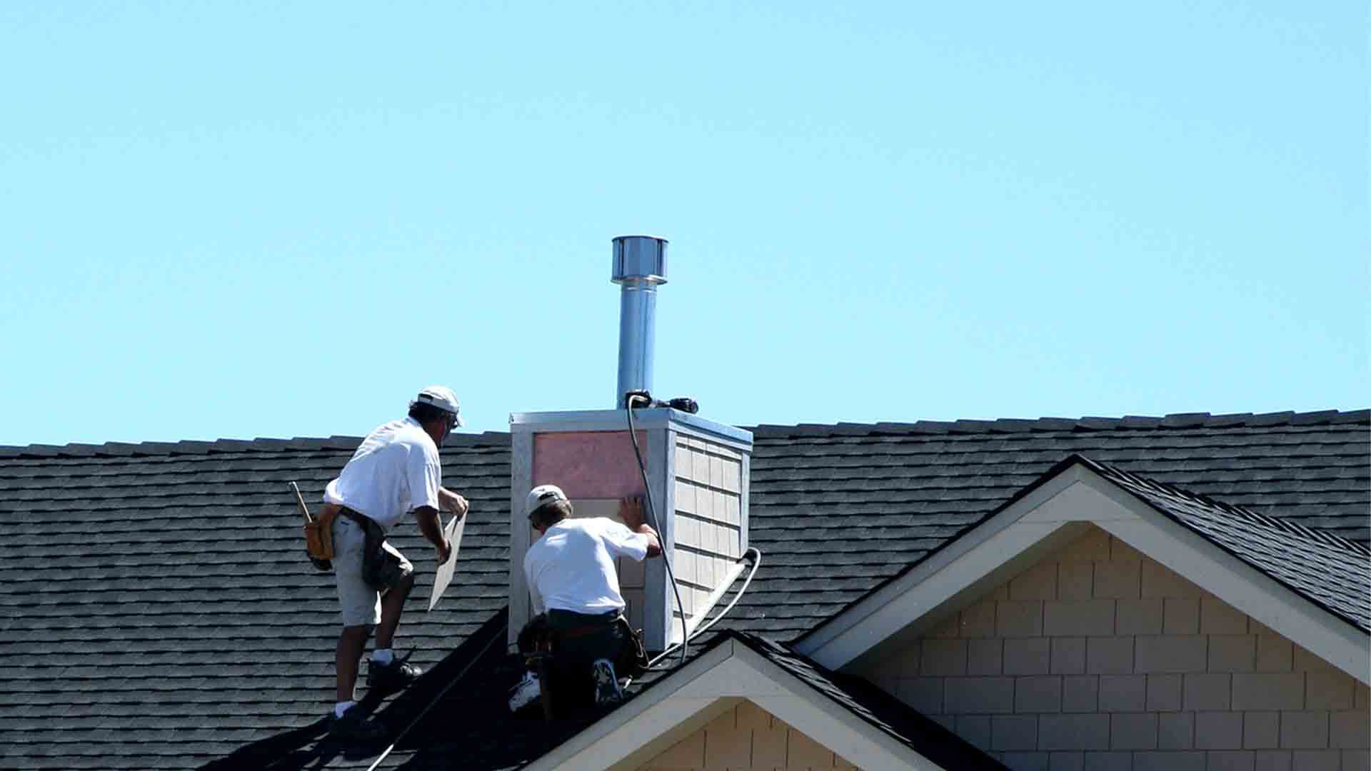 Dělníci na střeše vložkují komín